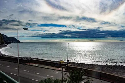 a road next to the ocean with a street light at Casa do Sol in Ponta do Sol