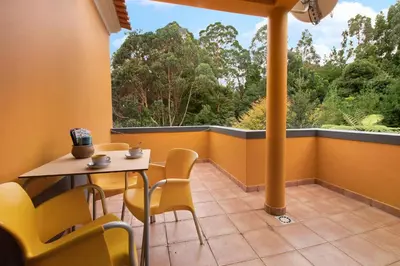 a balcony with a table and chairs and a large window at Casa Catarina in Santo da Serra