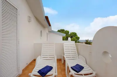 a balcony with white chairs and ladders on a building at Apartamento A Quinta Porto Santo in Campo de Baixo
