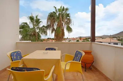 a balcony with a table and chairs and palm trees at Apartamento A Quinta Porto Santo in Campo de Baixo
