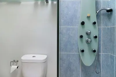 a bathroom with a shower with a toilet and a shower head at Villa Garajau House in Caniço