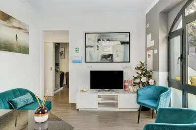 a living room with a television and blue chairs at Villa Garajau House in Caniço