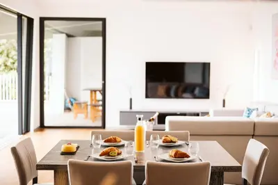 a dining room with a table with food and orange juice at Vila Aguarelas with pool by Stay Madeira Island in Arco da Calheta