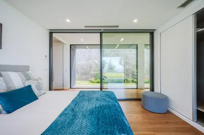a bedroom with a large white bed with a blue rug at Vila Aguarelas with pool by Stay Madeira Island in Arco da Calheta