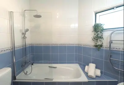 a blue tiled bathroom with a tub and a shower at Appartement Willy St. James Luz in Luz