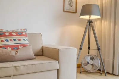 a room with a chair and a lamp and a fan at avenida arriaga 405 in Funchal