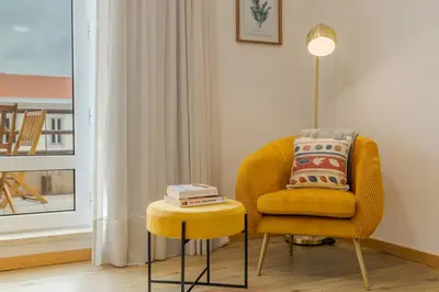 a yellow chair and stool in a room with a window at avenida arriaga 405 in Funchal