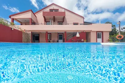 a house with a swimming pool in front of a house at Spacious House with Pool in Prazeres in Prazeres