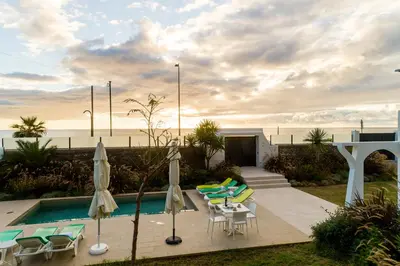a pool with chairs and umbrellas next to the ocean at Casa Paul do Mar in Paul do Mar