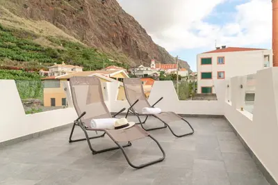 two chairs sitting on a balcony with a mountain at Casa Paul do Mar in Paul do Mar