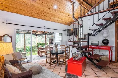 a living room with a spiral staircase and a table at Ivy Cottage by Homie in São Roque do Faial