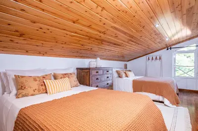 a bedroom with two beds and a wooden ceiling at Ivy Cottage by Homie in São Roque do Faial