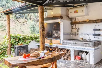 an outdoor kitchen with a table and a stove at Ivy Cottage by Homie in São Roque do Faial