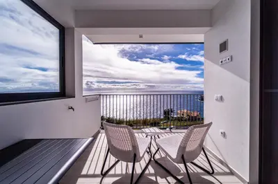 a balcony with two chairs and a table and a large window at Guesthouse Olival in Santa Cruz