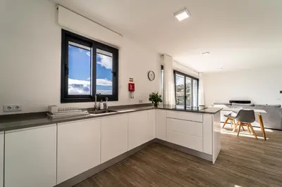 a kitchen with white cabinets and a large window at Guesthouse Olival in Santa Cruz