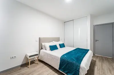 a white bedroom with a large bed with blue sheets at Guesthouse Olival in Santa Cruz