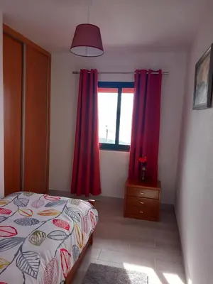 a bedroom with red curtains and a bed and a window at Casa dos Avós Domingos & Matilde in Estreito da Calheta