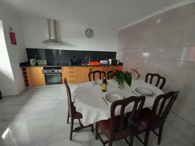 a dining room with a table and chairs and a kitchen at Casa dos Avós Domingos & Matilde in Estreito da Calheta