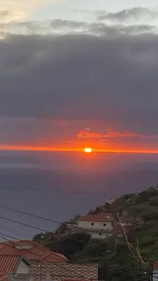 a sunset over the ocean with houses and buildings at Cozy 1 BR w/ balcony, ocean view & perfect sunsets in Ribeira Brava