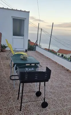 a grill on a patio with a view of the ocean at Cozy 1 BR w/ balcony, ocean view & perfect sunsets in Ribeira Brava