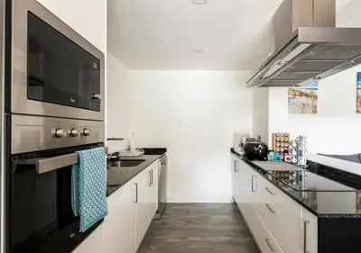 a kitchen with white cabinets and a black stove top oven at Lovely 1-bedroom apartment with parking ocean view in Funchal