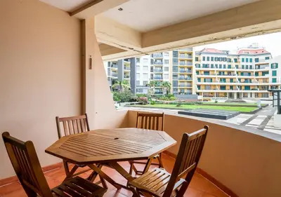 a wooden table and chairs in a room with a large window at Lovely 1-bedroom apartment with parking ocean view in Funchal