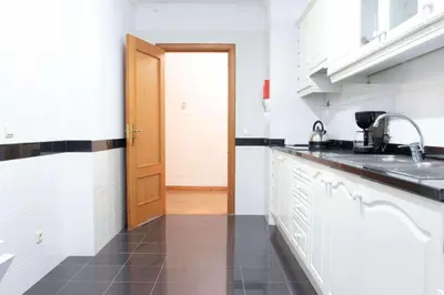 a kitchen with white counters and a wooden door at Elsas Place in Funchal