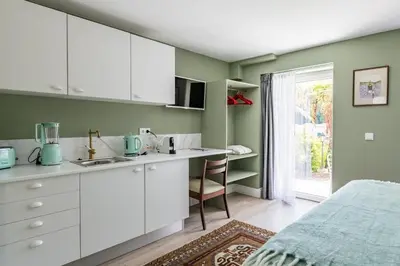 a kitchen with white cabinets and a bed in a room at Villa Camélia Boutique House in Camacha