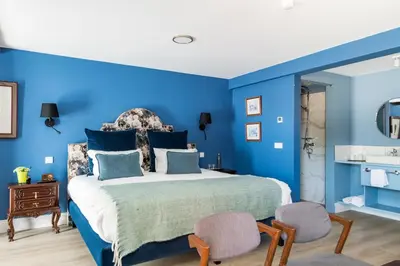 a blue bedroom with a bed and two chairs at Villa Camélia Boutique House in Camacha