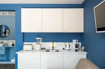 a kitchen with white cabinets and blue walls at Villa Camélia Boutique House in Camacha