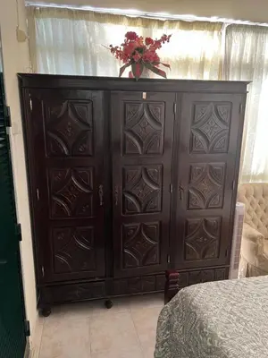 a large wooden cabinet with a vase of flowers on top at Angie’s apartment in Funchal