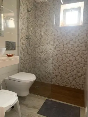 a bathroom with a toilet and a glass shower at ORANGE guest house in Sagres
