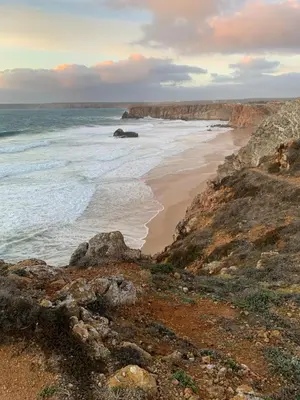 a beach with rocks and the ocean on a cloudy day at ORANGE guest house in Sagres