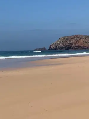 a beach with the ocean and rocks in the background at ORANGE guest house in Sagres
