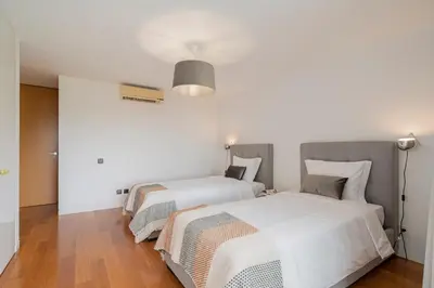 two beds in a bedroom with white walls and wood floors at Villa das Quebradas by An Island Apart in Funchal