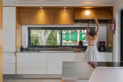 a woman standing in a kitchen looking out a window at Villa das Quebradas by An Island Apart in Funchal