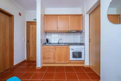 a kitchen with wooden cabinets and a tile floor at Porto Moniz City Centre by Homie in Porto Moniz