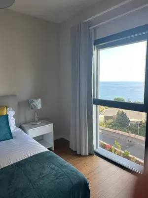 a bedroom with a bed and a large window at Ines Seaview Apartment in Funchal