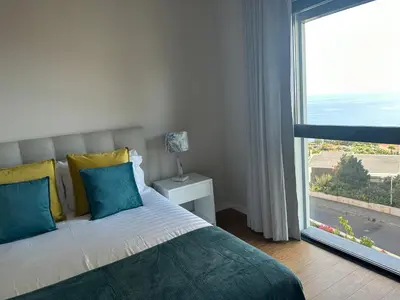 a bedroom with a bed and a large window at Ines Seaview Apartment in Funchal
