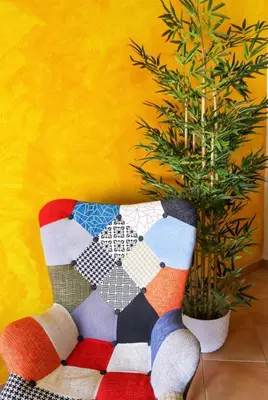a colorful chair next to a plant in a yellow wall at Arrifana Beach House - T2 Haller in Aljezur