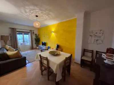 a living room with a table and a yellow wall at Arrifana Beach House - T2 Haller in Aljezur