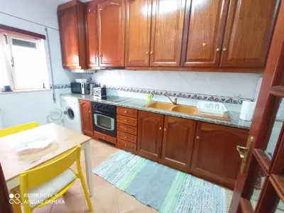 a kitchen with wooden cabinets and a sink and a table at Arrifana Beach House - T2 Haller in Aljezur