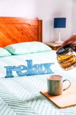 a bed with a cup of coffee and the word relax at Arrifana Beach House - T2 Haller in Aljezur