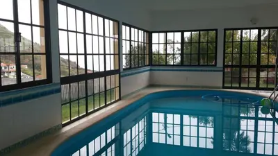 a large swimming pool in a building with windows at House pc in Porto da Cruz