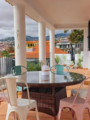 a patio with a glass table and chairs on a balcony at Villa Carvalhal in Funchal