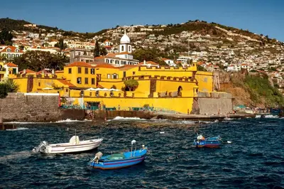 three boats in the water in front of a yellow building at Villa Carvalhal in Funchal