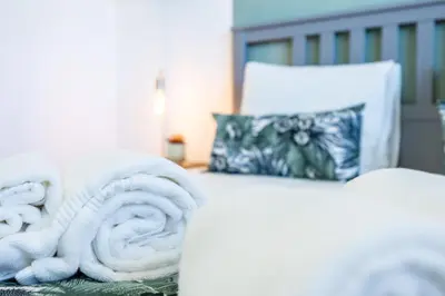 a white bed with a pile of towels on it at The Kuuyi Suite in Burgau