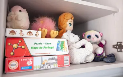 a shelf with stuffed animals and books on it at The Kuuyi Suite in Burgau