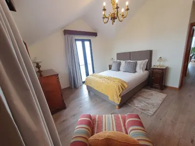 a bedroom with a bed and a couch and a chandelier at Ocean View Madeira 1 - Ponta do Sol in Canhas
