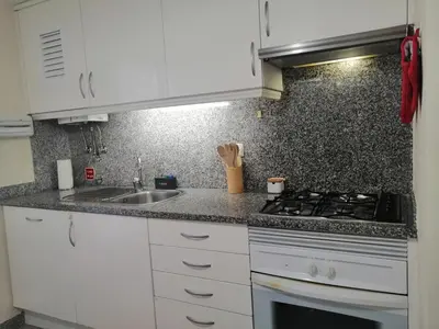 a kitchen with white cabinets and a sink at Duplex da Fontinha in Santa Cruz